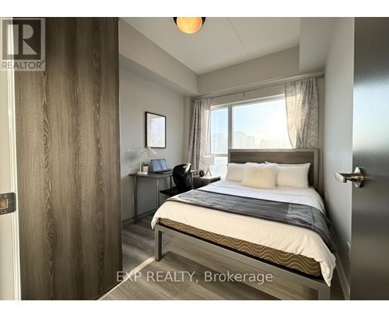 A bedroom with a bed, desk, and window.