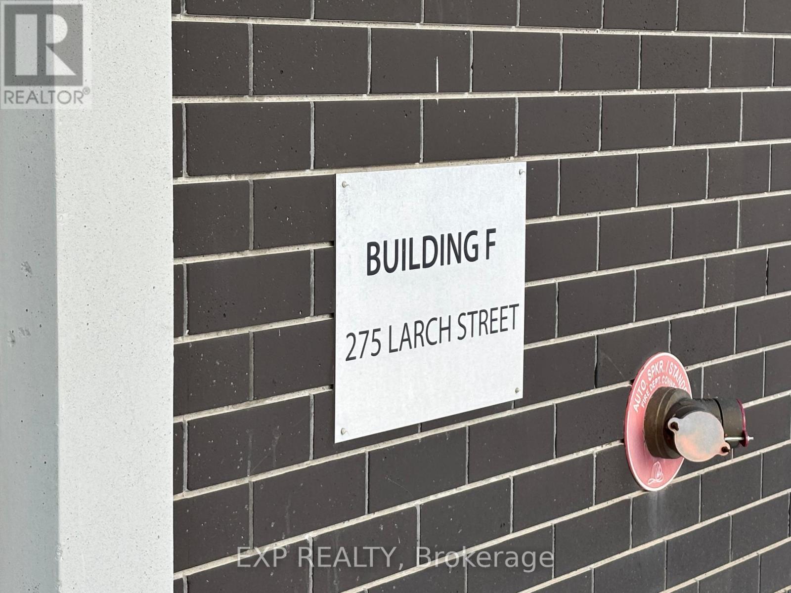 A sign on a brick wall that says Building F 275 Larch Street.