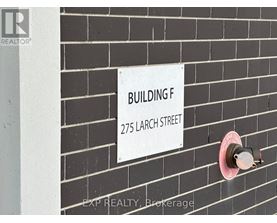 A sign on a brick wall that says Building F 275 Larch Street.