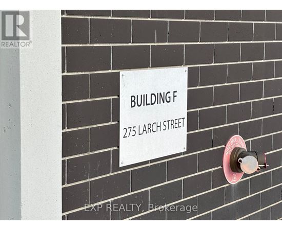 A sign on a brick wall that says Building F 275 Larch Street.
