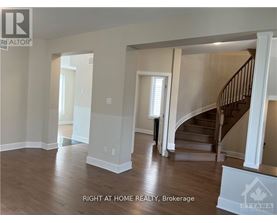 A spacious room with a staircase and a window.