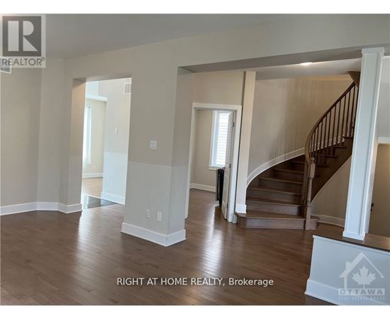 A spacious room with a staircase and a window.