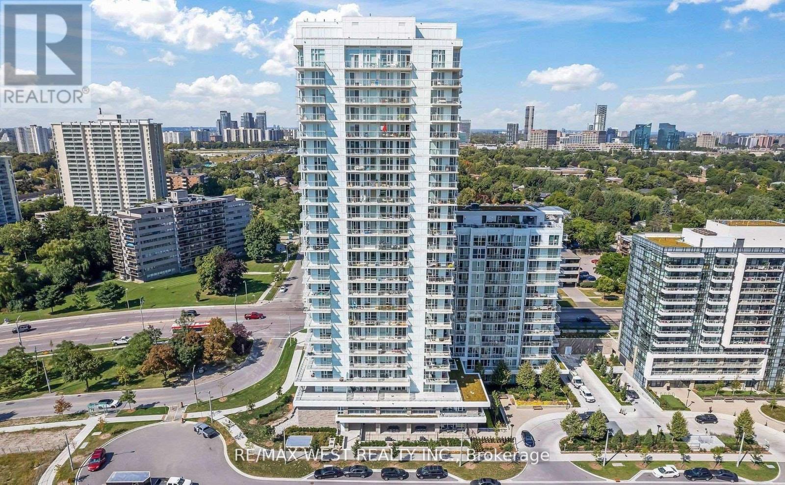 A tall residential building with a glass facade stands in the foreground of a cityscape.