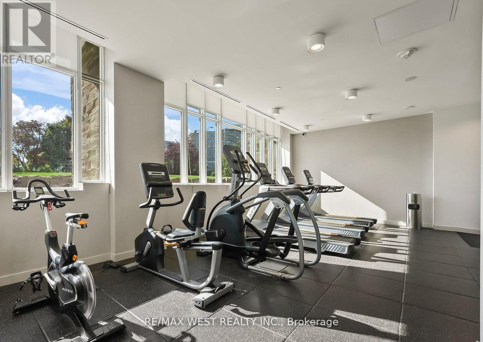 A gym with a treadmill, exercise bike and elliptical trainer.