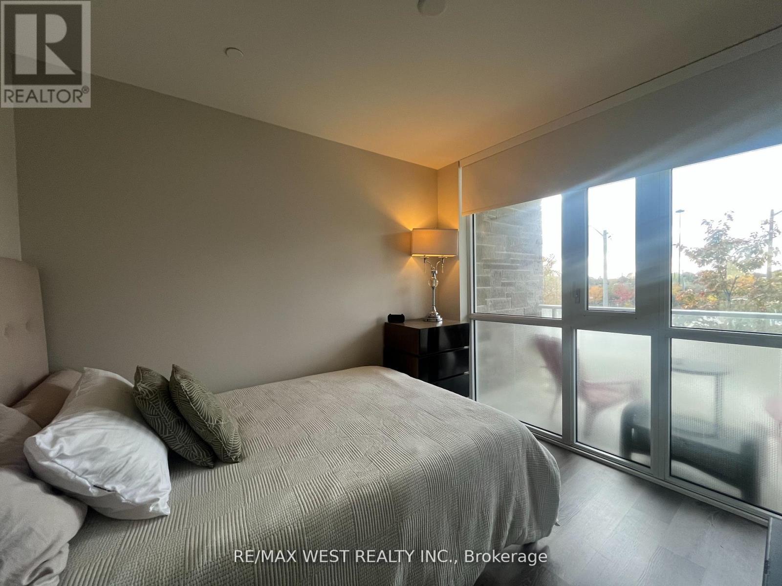 A bedroom with a bed, nightstand, and window.