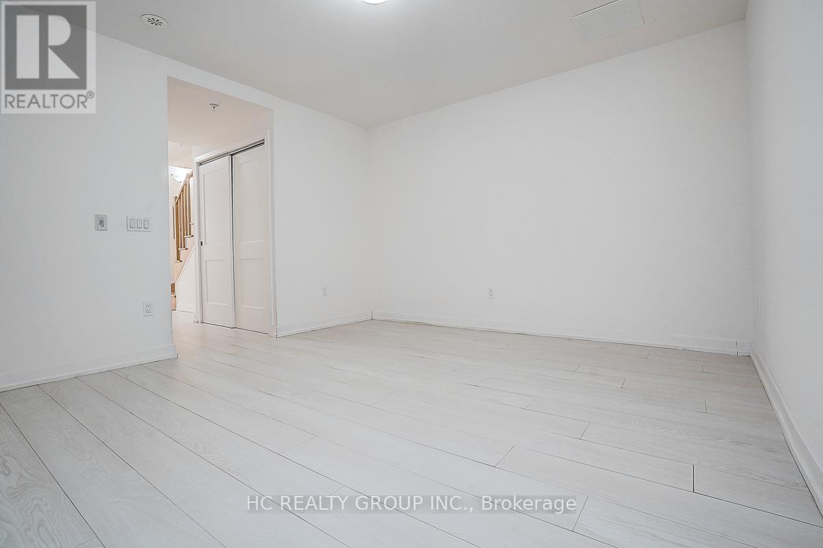 A spacious room with white walls and wooden flooring.