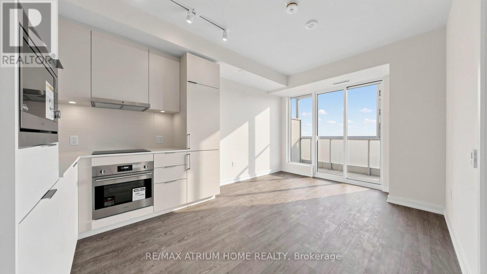 A spacious kitchen with white cabinets and a large window.