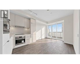 A spacious kitchen with white cabinets and a large window.