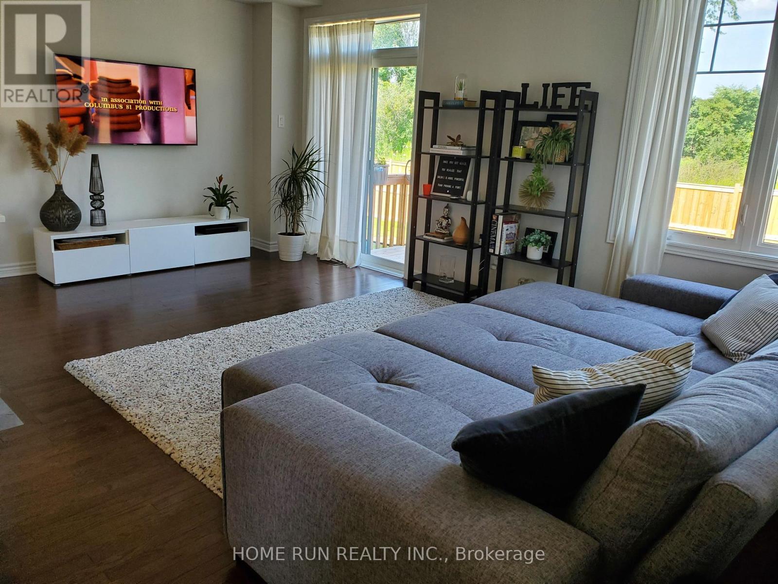 A living room with a grey couch and a wooden floor.