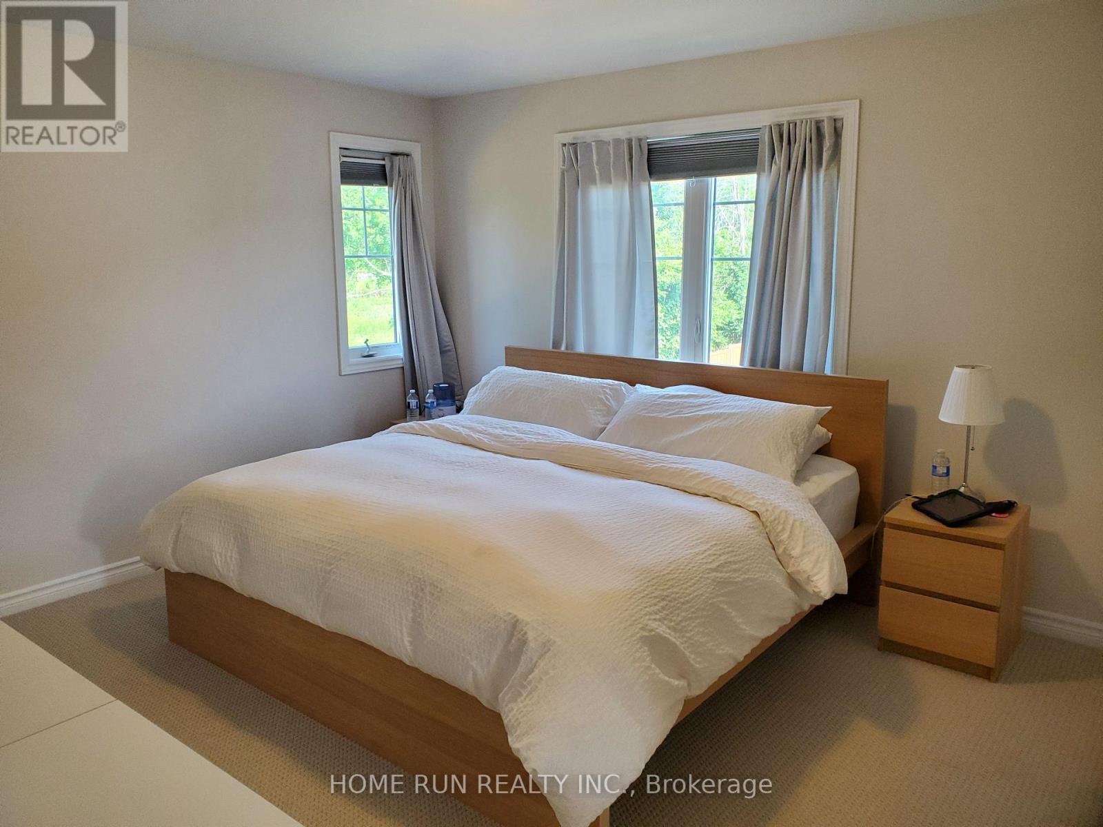 A bedroom with a large bed, nightstand, and window.