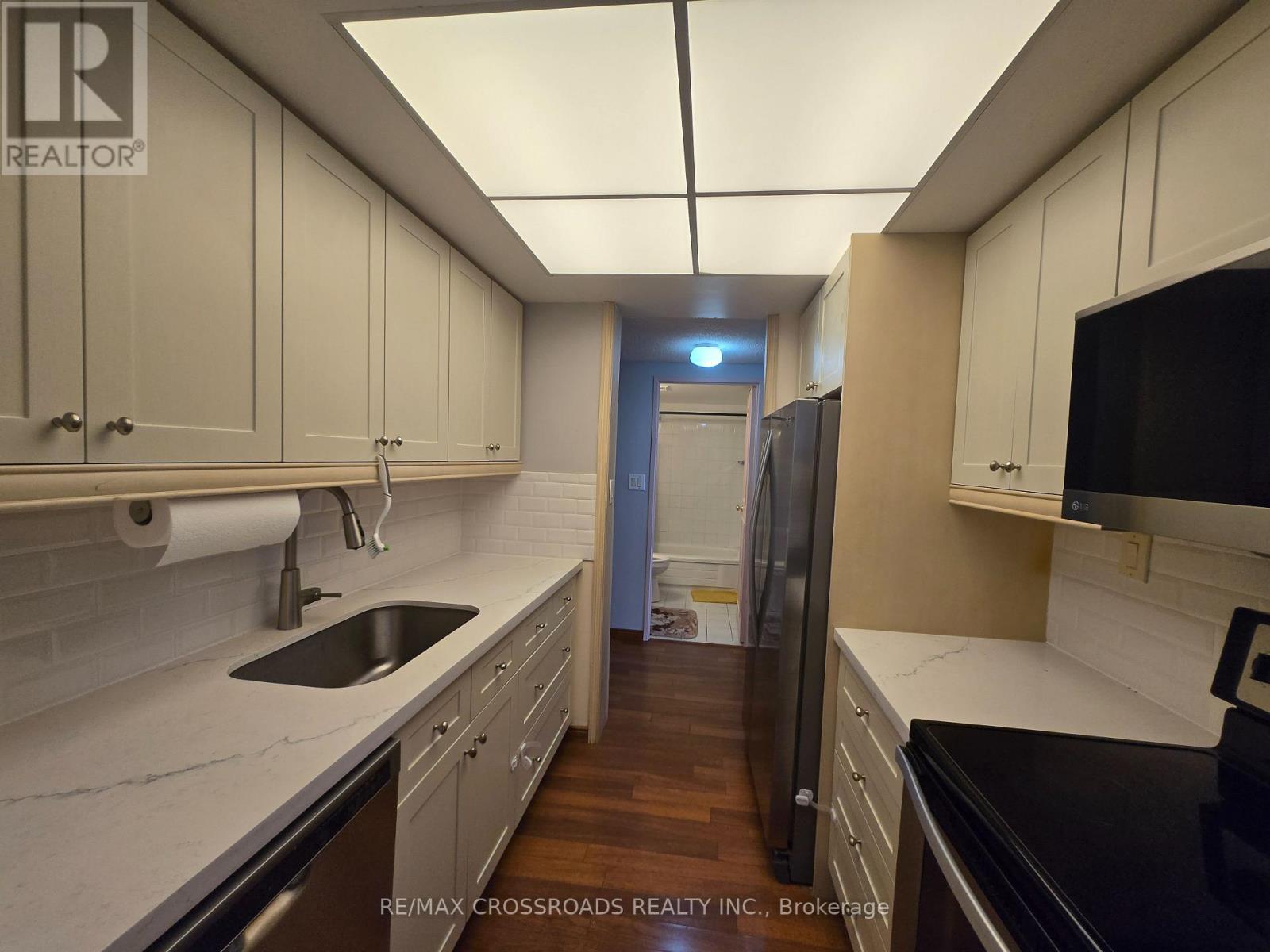 A kitchen with white cabinets and a black refrigerator.