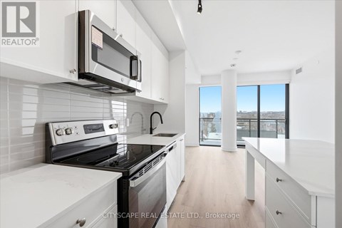 A modern kitchen with white cabinets and a black stove top oven.