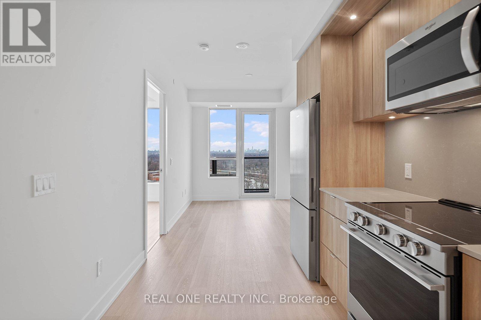 A spacious lobby with a staircase and a large window overlooking a cityscape.