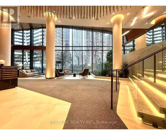 A spacious lobby with a staircase and a large window overlooking a cityscape.