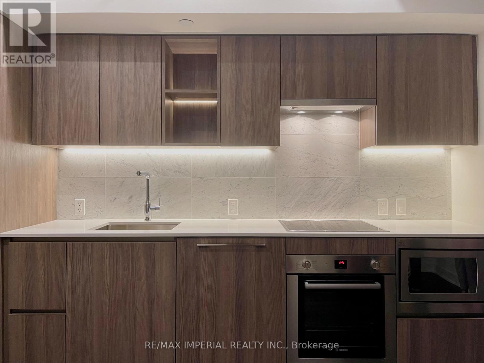 A modern kitchen with wooden cabinets and a marble backsplash.