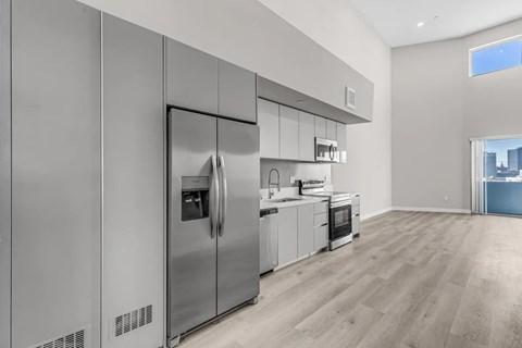 A modern kitchen with stainless steel appliances and wooden flooring.