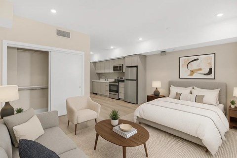 A well-lit bedroom with a large bed, a chair, a couch, and a coffee table.