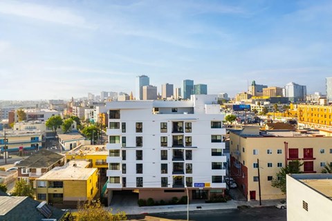 A white building with many windows is in the foreground of a cityscape.