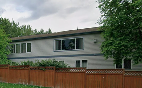 A grey house with a brown fence in front of it.