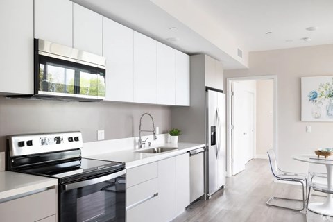 A modern kitchen with white cabinets and a black stove top oven.