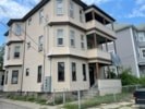 A beige two story house with a balcony on the second floor.