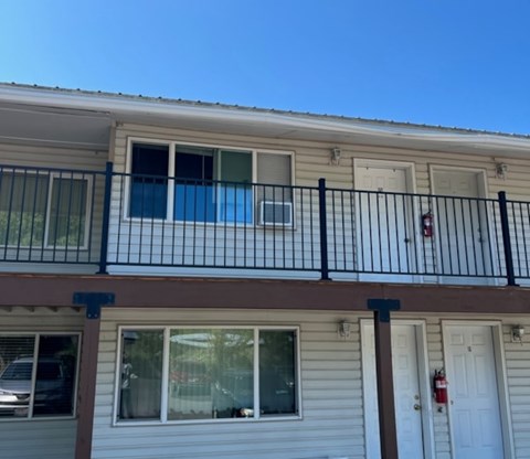 A balcony with a black railing and a red fire extinguisher on the wall.