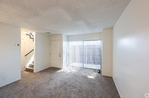 A room with a carpeted floor and a sliding glass door.