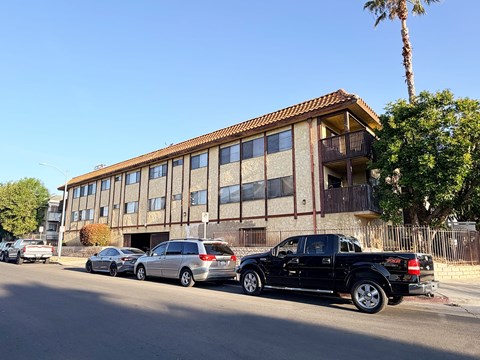A black truck is parked in front of a building with a palm tree in the background.