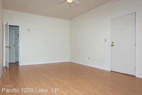 A room with wooden flooring and two doors, one of which is open.