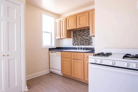 A kitchen with a white stove and wooden cabinets.