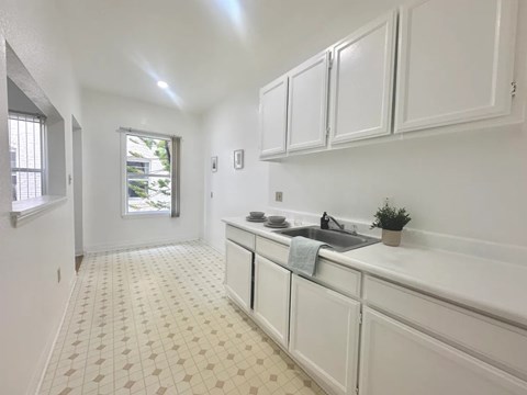 A kitchen with white cabinets and a tiled floor.