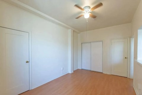 A room with a ceiling fan and wooden floors.