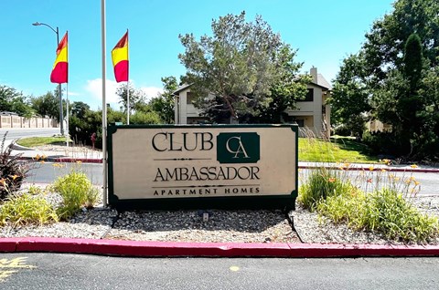 A sign for Club Ambassador Apartment Homes is displayed in front of a building.