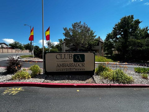 A sign for Club Ambassador Apartment Homes is displayed in front of a building.