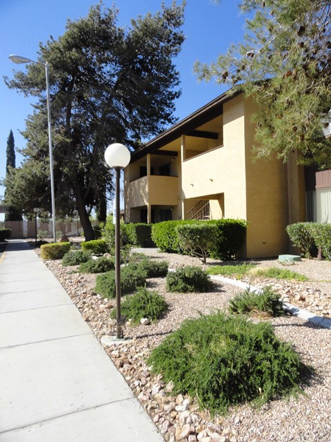 A white lamp post stands on a sidewalk in front of a tan building.