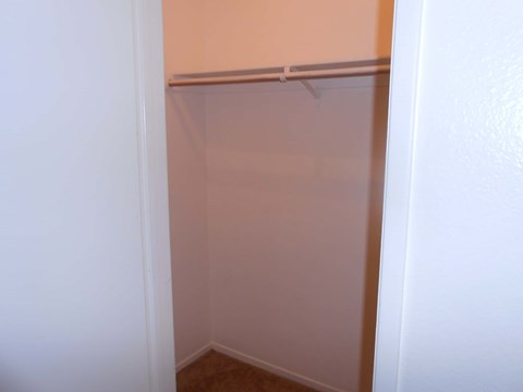 A white door is open to a room with a white wall and a white shelf.