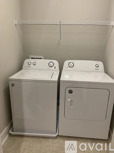 Two white front loading washing machines in a laundry room.