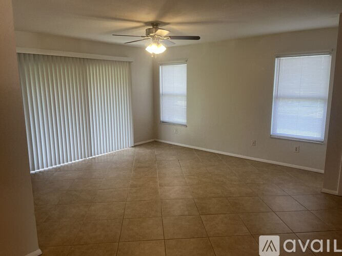 A room with a ceiling fan and two windows.
