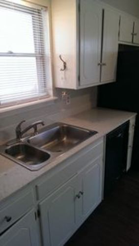 A kitchen with white cabinets and a stainless steel sink.