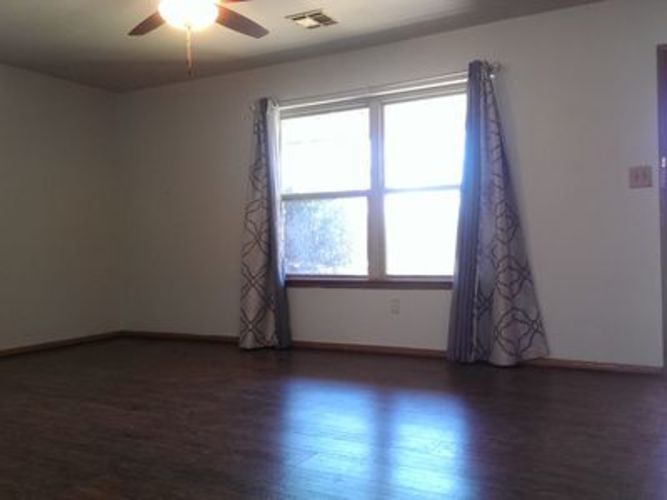 A room with a window and curtains.
