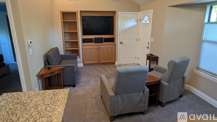 A living room with a grey couch, a wooden entertainment center, and a carpeted floor.