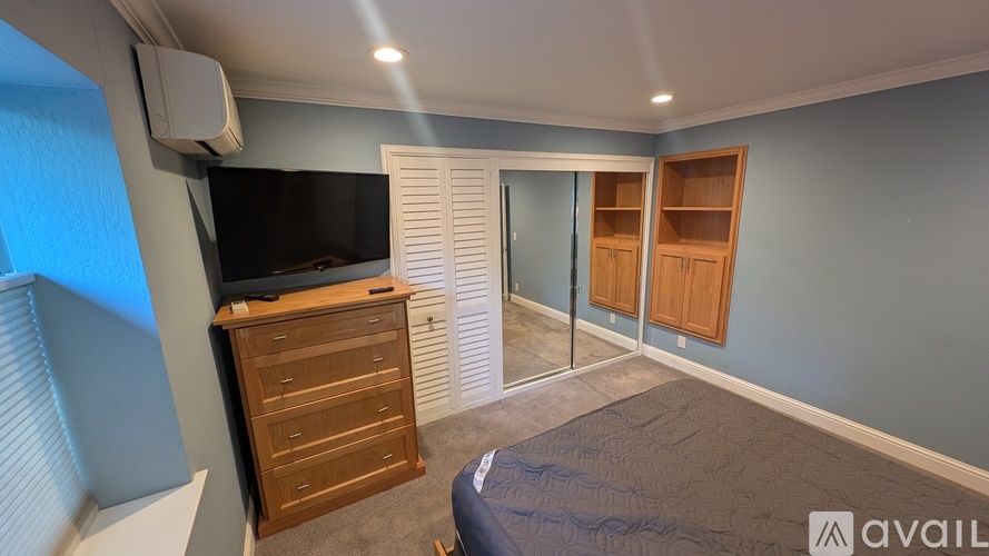 A bedroom with a bed, a dresser, and a television.
