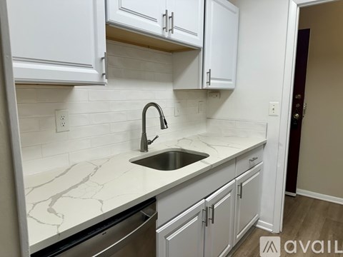 A kitchen with white cabinets and a marble countertop.