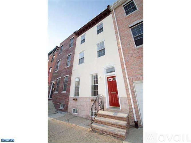 A red door is on the front of a white building.