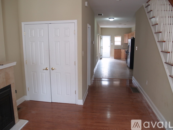 A hallway with a wooden floor and a staircase on the right side.