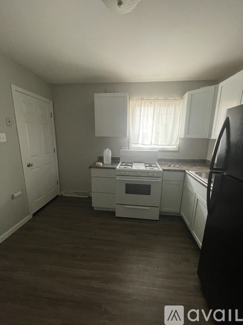 A kitchen with white cabinets and a black refrigerator.