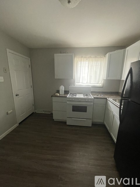 A kitchen with white cabinets and a black refrigerator.