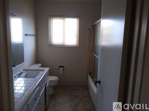 A bathroom with a toilet, sink, and window.