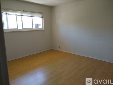 A room with wooden flooring and a window with blinds.