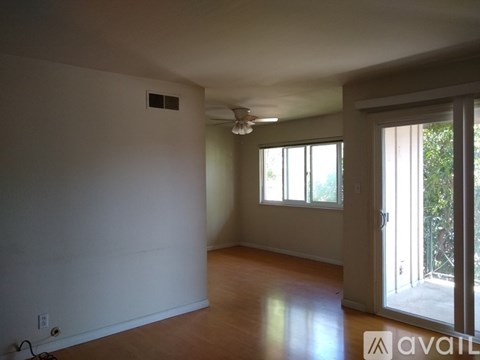 A room with a ceiling fan and sliding glass doors.